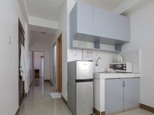 马尼拉Alicia Apartment的白色的厨房配有冰箱和微波炉。
