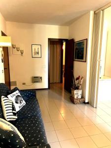 蓬塔阿拉Punta Ala Flat的客厅配有黑色沙发和瓷砖地板。