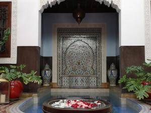 马拉喀什东方魅力摩洛哥住宅酒店 - 仅限成人的一间大地毯的房间,墙上有一个喷泉