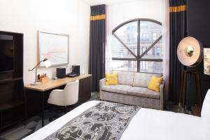 密尔沃基Saint Kate - The Arts Hotel的酒店客房配有一张床、一张书桌和一张沙发。