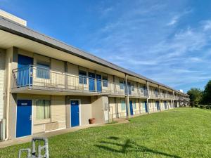 福雷斯特城Motel 6 Forrest City AR的一座长长的建筑,有蓝色的门和草地