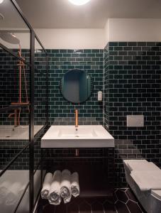 鹿特丹FD Hotels的黑色瓷砖浴室设有水槽和镜子