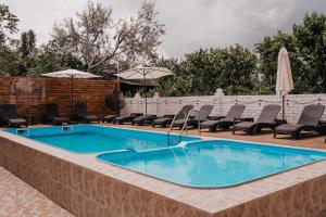 扎托卡Villa "White Pearl"的庭院内一个带椅子和遮阳伞的游泳池