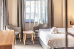 悉尼Lakemba Hotel的酒店客房设有一张床、两把椅子和一扇窗户。