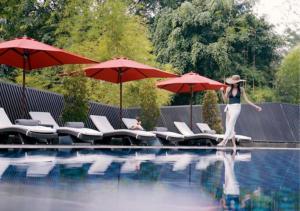 雅加达雅加达美利亚酒店&度假村的一位妇女走进一个游泳池,那里有红伞
