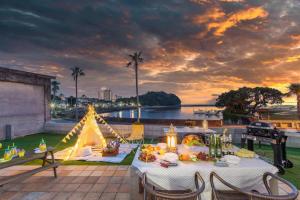 白滨West Coast Villa Shirahama的露台上的一张桌子和一张帐篷,享有日落美景
