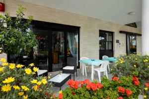 萨包迪亚Hotel Il Gabbiano的庭院配有桌椅和鲜花