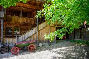 泽拉夫纳Guest Houses "Zlatna Oresha - Complex"的前面有一辆红色的马车的木制建筑