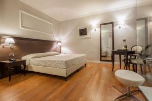 佛罗伦萨伦巴蒂酒店的卧室配有1张床、1张桌子和1把椅子