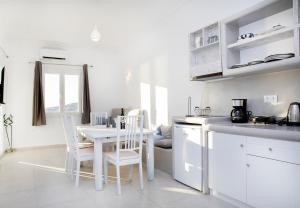 帕罗奇亚Crystal Dreams的厨房配有白色橱柜和桌椅