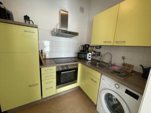 莱比锡LE-Citywohnung-II的厨房配有黄色橱柜和洗衣机。
