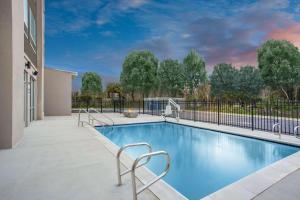马纳萨斯La Quinta Inn & Suites by Wyndham Manassas, VA- Dulles Airport的一座带椅子的游泳池,位于大楼旁