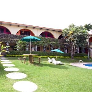 休特佩克Hotel & Motel Hacienda Jiutepec的一个带椅子和遮阳伞的庭院和一个游泳池