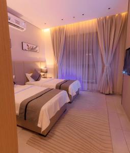利雅德فيفيان بارك الروابى Vivian Park Al Rawabi的酒店客房设有两张床和电视。