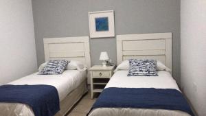 塞博河畔卡莱塔Apartamentos Burgao的一间卧室配有两张床和一张带台灯的桌子
