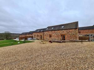 阿什比德拉祖什Hastings Retreat Rural barn conversions with Private Lake的砖砌谷仓前设有野餐桌