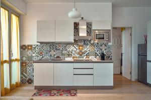 米兰Skyline Apartment的厨房配有白色橱柜和瓷砖墙。