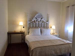 布拉加Bracara luxury guesthouse的一间卧室配有一张带两盏灯的大型白色床。