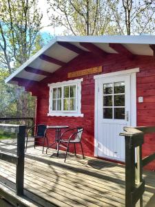 阿克雷里Bakkakot 3 Cozy Cabin In The Woods的红色小屋,甲板上配有桌椅
