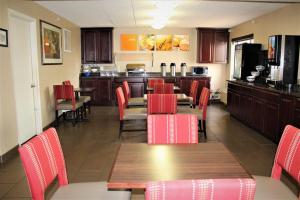 费尔法克斯大学中心康福特茵酒店的一间带红色桌椅的餐厅和一间厨房