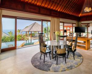 乌鲁瓦图巴厘岛边缘别墅的一间带桌椅的用餐室和一个阳台