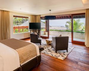 乌鲁瓦图巴厘岛边缘别墅的一间卧室配有一张床、两把椅子和电视