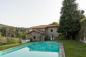 维拉诺瓦-德法马利Quinta de Pindela - Natureza e Tradicao的石头房子前的大型游泳池