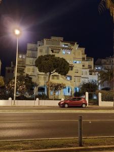 埃尔波提尔Playa entre pinares的夜间停在大楼前的红色汽车