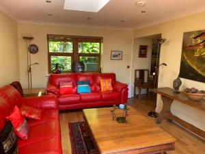 芬德霍恩Abbey Cottage, Findhorn的客厅配有红色皮革沙发和桌子
