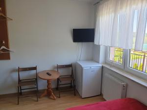 波莫瑞地区卡缅POKOJE U MIKOŁAJA的一间设有桌子和两把椅子、一张小桌子和两个窗户的房间