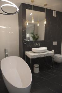 贝图夫Atmosfera Apartament 4的浴室设有白色浴缸、水槽和镜子