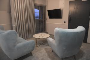 贝图夫Atmosfera Apartament 4的客厅配有两把椅子和电视