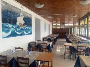 德瓦玛丽娜卡拉唯拉酒店的用餐室配有桌椅,墙上挂有绘画作品