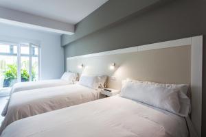 菲尼斯特雷Hospedium H Cabo Sport的配有2张床的白色墙壁和窗户。