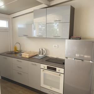 莫鲁纳特Apartments Rašica的厨房配有白色橱柜和不锈钢冰箱