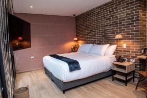 Carmen de ViboralCasa Rosé Hotel的一间卧室设有一张大床和砖墙