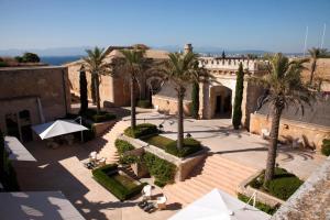 卡拉布拉瓦Cap Rocat, a Small Luxury Hotel of the World的庭院里种有棕榈树,配有桌子和遮阳伞
