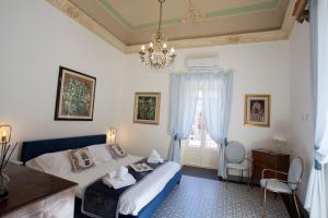 拉古萨Palazzo d'Autore - Luxury Home - Ragusa Centro的一间卧室配有一张床和一个吊灯