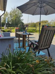 卡兰茨奥赫B&B Buiten Gewoon Callantsoog的桌子和带雨伞的椅子