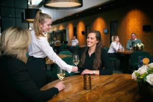 鹿特丹鹿特丹凡德瓦克酒店的两个女人坐在桌子上,戴着酒杯