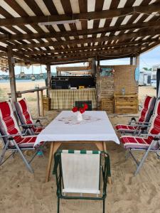 索佐波尔Ultimate Caravan Experience - 1st Line Gradina的海滩上的桌椅,配有白色的桌子和椅子