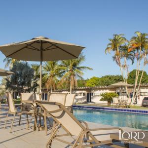 泰谢拉迪弗雷塔斯Hotel Pousada Lord的一组椅子和一把遮阳伞,位于游泳池旁