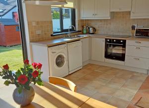 考敦Beachside Avenue Holiday Home No 15的厨房配有洗衣机和带花瓶的桌子。