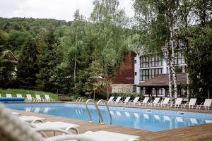 亚列姆切亚列姆切俱乐部酒店的一座带白色椅子的游泳池和一座建筑