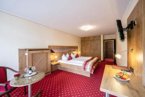 贝希特斯加登Hotel AlpinaRos的酒店客房配有一张床铺和一张桌子。