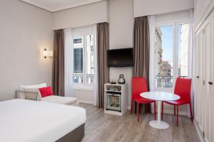马德里Hotel Madrid Gran Via 25, Affiliated by Meliá的酒店客房带一张床、一张桌子和椅子