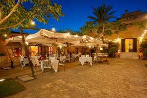马尔萨拉Hotel Baglio Oneto dei Principi di San Lorenzo - Luxury Wine Resort的一间晚上配有白色桌椅的餐厅