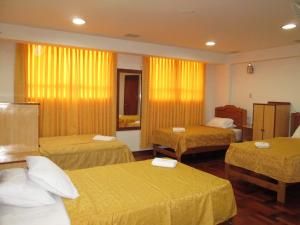 利马泛美酒店 的酒店客房,设有三张带黄床单的床