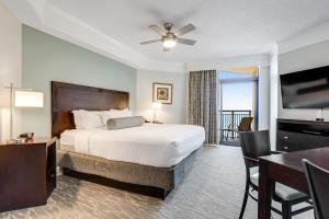 默特尔比奇Anderson Ocean Club and Spa by Oceana Resorts的配有一张床、一张桌子和一张桌子的酒店客房