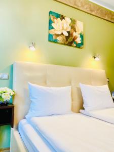 锡比乌Style Residence的一张带白色枕头的床和墙上的绘画